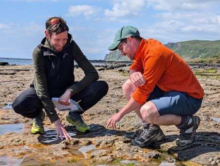 two men examine a chirotherium footprint near the coast