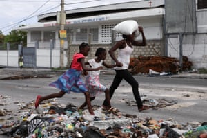 A woman and two children flee their homes in the Lower Delmas, Port-au-Prince, Haiti, due to gang violence.