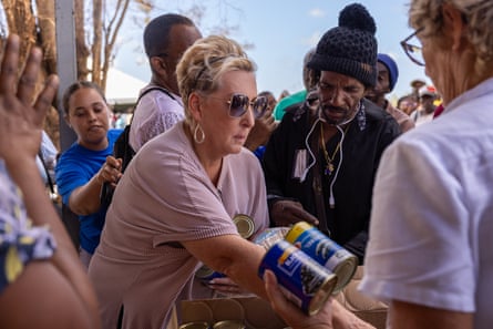 woman holds cans of food as people stand by