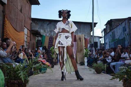 A woman poses wearing a a skirt and top made of repurposed cloth.