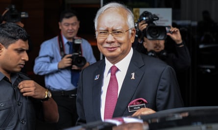 Najib Razak, smiling, with photographers in background