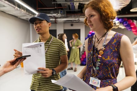 Aidan, wearing a stripy T-shirt, and Fran, wearing a purple summer dress, hold the A4 pieces of paper with their A-level results on them.