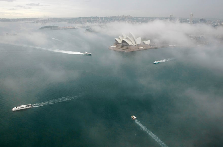 Boats in the harbour pass in front of the Sydney Opera House on a foggy morning in June 2008.