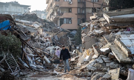 A man walks past collapsed buildings in Hatay, Turkey.