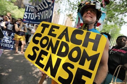 A man holds a sign that reads ‘teach condom sense’
