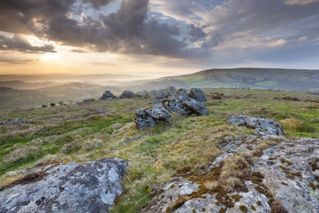 Duck's Pool Dartmoor National Park, Hayne Down, Sunrise over hilly landscape with mossy rocks in foreground