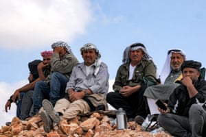 Men sitting and crouching on a hilltop