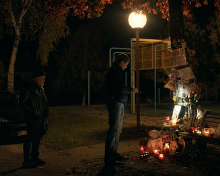 People standing in front of a memorial with candles and cards