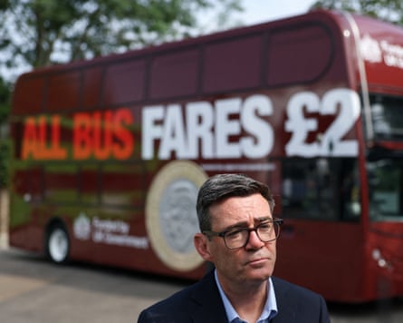 Burnham standing in front of a bus emblazoned with the words ‘all bus fares £2’