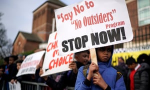 Child holds banner saying 'Say no to no outsiders'