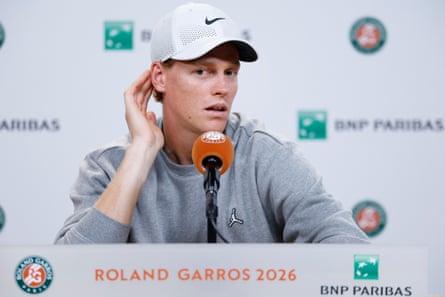 Jannik Sinner cups his hand to his ear in a press conference at the French Open