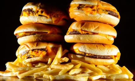 A pile of cheeseburgers and french fries.