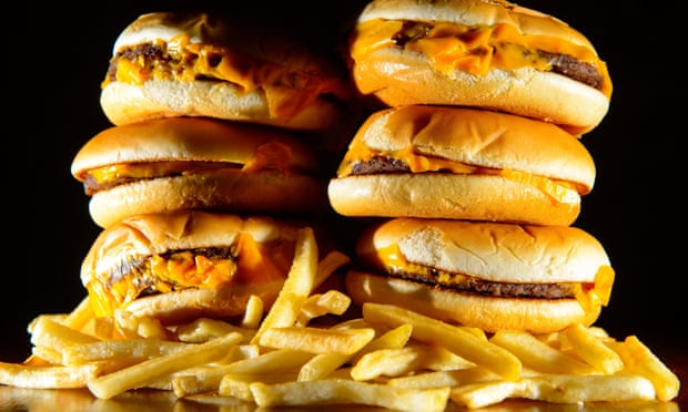 a pile of cheeseburgers and french fries, as advertising unhealthy foods during family TV shows should be banned, MPs have said, as they called on the Government to introduce a “sugar tax” on soft drinks.