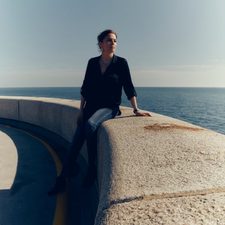 Woman wearing black shirt and jeans sitting on a stone wall overlooking the sea in Folkestone, 23 September 2026