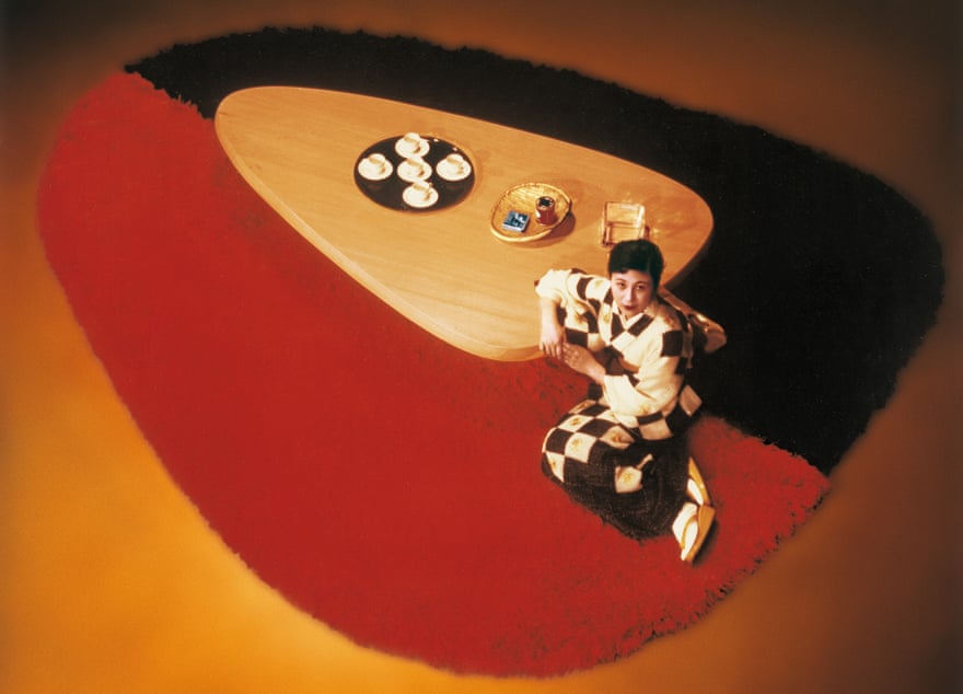 A model poses with a hinoki wood table and wool rug, circa 1955, by Charlotte Perriand.