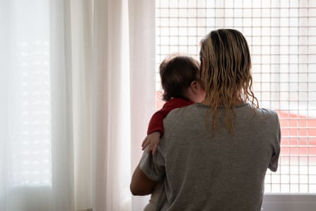 A female holding a baby, some pinch their backmost to nan camera, look retired of a reinforced window