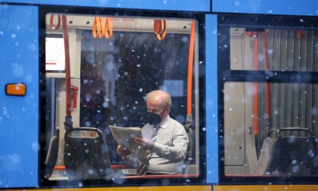 Man wearing a protective face mask rides on a tram during a snowfall in Sofia, Bulgaria on Wednesday. He wears a shirt and tie.