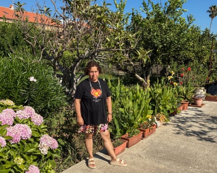 Rosa Cattafi, 66, stands in a garden surrounded by flowering plants and trees.