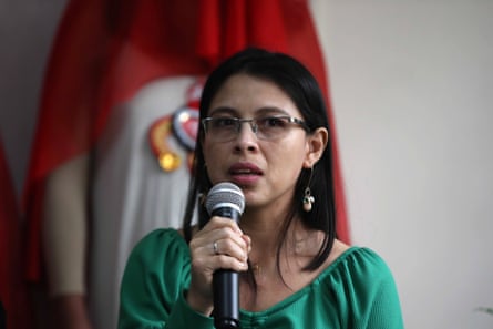 A woman wearing a green shirt speaks into a microphone.