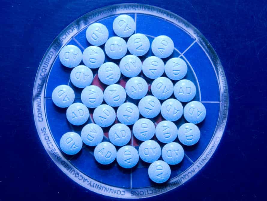 A dish of white tablets is bathed in a bluish light.