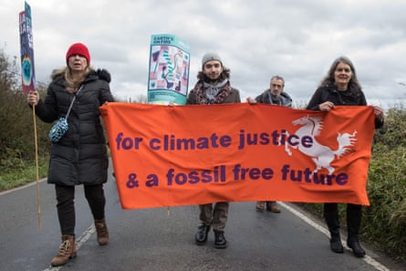 Four activists hold a banner reading ‘for climate justice & a fossil free future’