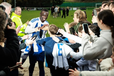 Fans take photos and ask Papiss Cissé for autographs as he exits the pitch at the end of the match against South Liverpool
