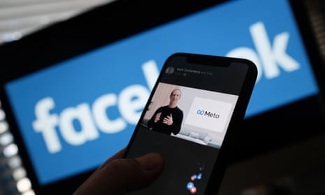 A person watches on a smartphone as Facebook CEO Mark Zuckerberg unveils the Meta logo. 
