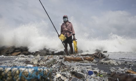 A man fishes on a beach covered with plastic pellets