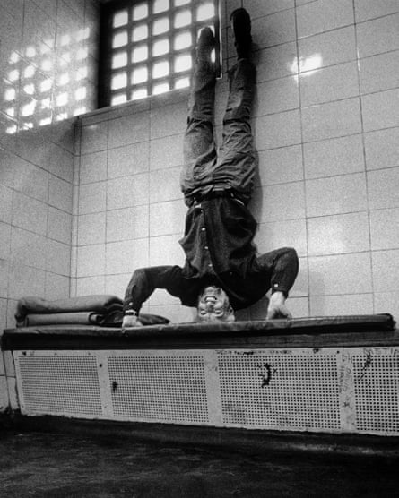 Photographer David Hoffman, doing a headstand on a bench in a cell at Southwark police station, after being arrested at anti-Satanic Verses protests on 27 May 1989