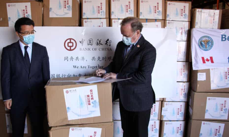 Li Aihua, president of Bank of China (Canada), poses with Lee Errett, a Canadian official, in front of boxes of Chinese medical supplies in Toronto. The Bank of China donated 7.5 tonnes of medical supplies to Canada.