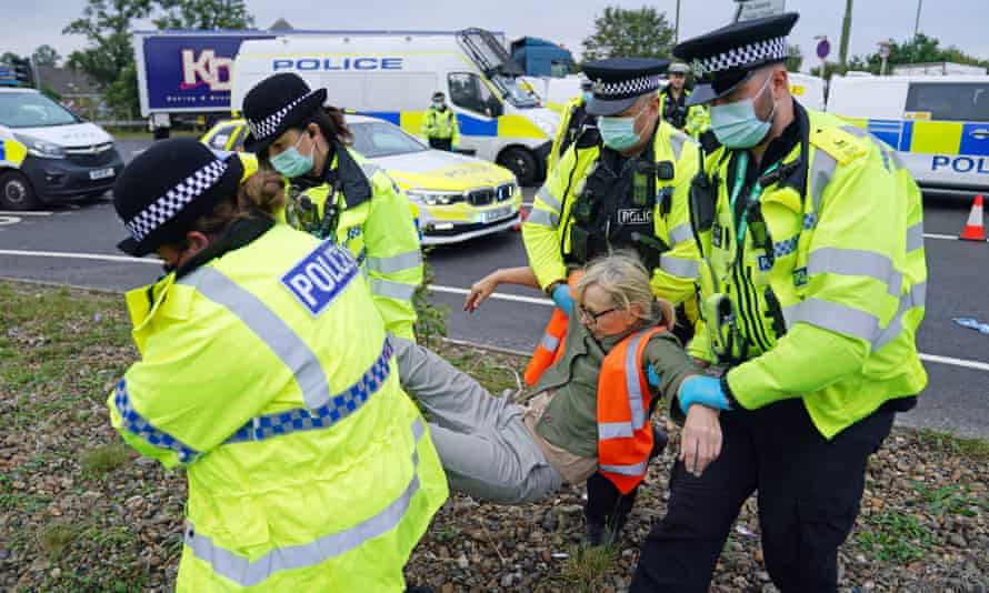 Police officers carry away one of a number of protesters who had glued themselves to the highway near junction 4 of the A1(M) near Hatfield, Hertfordshire