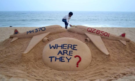 Indian sand artist Sudarsan Pattnaik gives the final touches to his sand sculpture portraying two missing aircraft, Air Asia QZ8501 and Malayasia Airlines MH370.
