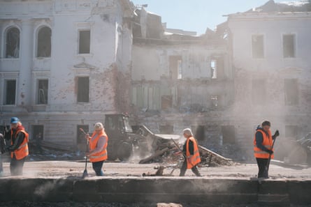 Locals remove the debris at the street damaged by rocket hits in Sumy