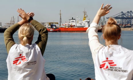 Two women wearing Médecins Sans Frontières T-shirts wave to the Aquarius relief ship in the port of Valencia, Spain