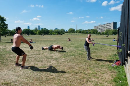 Three people work out in Burgess Park, south London, in May