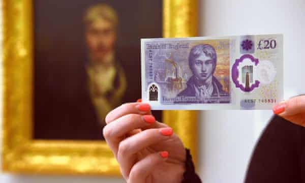 A person holds the polymer £20 note in front of a portrait of the artist JMW Turner at the Tate Britain in London.