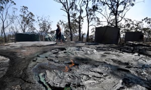 Jeanette Schwindt inspects the remnants of their burnt water tanks after a bushfires swept through the area the day before in Mount Larcom.