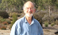 Portrait of Hugh Saddler, outside wearing glasses and a blue shirt with bush landscape behind him.