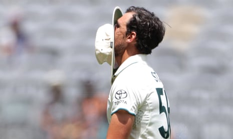 Mitchell Starc hides his face in his hat after a poor over.