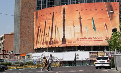 a couple walks past a billboard depicting missiles