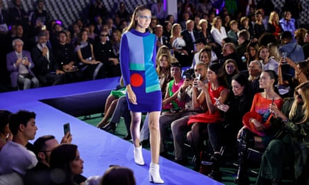 A model on the catwalk in a blue knitted jumper dress with a bold graphic design