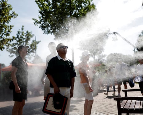 Roland Garros spectators cool down by a water spray station during heatwave in Paris.