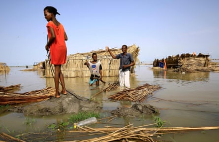 South Sudanese refugees repair their hut in flood waters from the White Nile at a refugee camp in al-Qanaa, southern Sudan, in 2021.