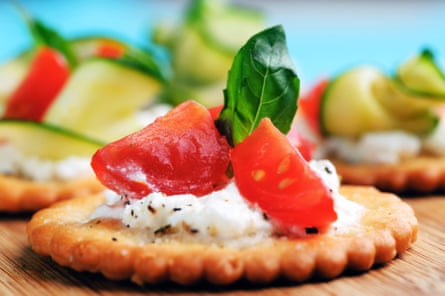 Canape ukuran gigitan dengan keju ricotta dan tomat yang dihias dengan kemangi