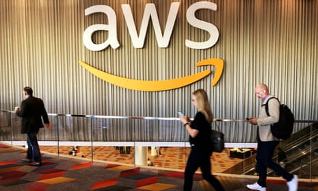 AWS logo on wall as workers walk by at conference