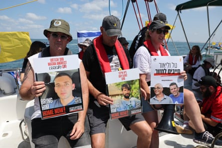 People holding pictures of their loved ones with the words: “bring him home now”, on a boat