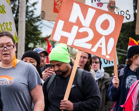 people hold signs in protest of H-2A