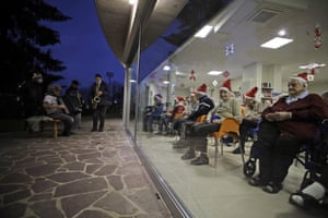 Residents of a care home in Bergamo, Italy, attend a Christas concert from behind a glass window