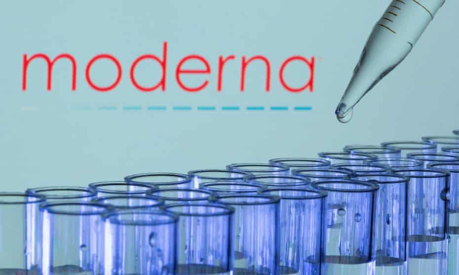 Test tubes are seen in front of a displayed Moderna logo