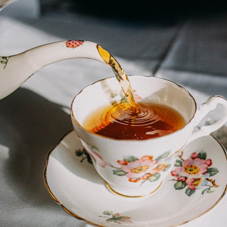 Vintage teapot pouring tea in teacup.